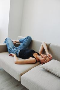 Low section of woman sitting on sofa at home