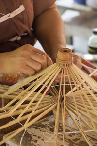 Cropped image of woman making umbrella at workshop