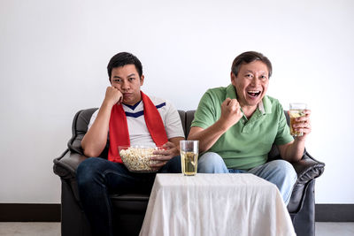 Family with food and drink watching sports on tv at home