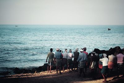 Fishermen pulling rope from sea while standing at shore