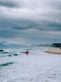 People kayaking in sea against sky