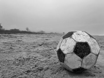 Close-up of soccer ball at sandy beach against sky