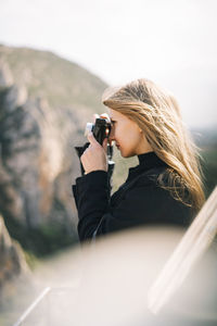 Midsection of woman photographing against sky