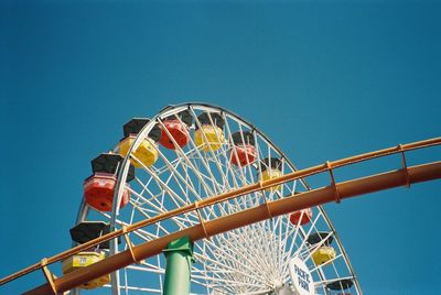 Low angle view of ferris wheel against blue sky