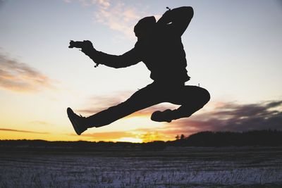 Silhouette of man jumping against sunset sky