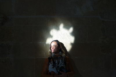 Sunlight falling on mid adult woman by wall