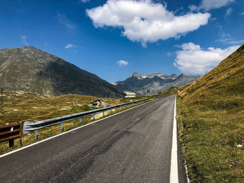 Empty road along landscape and mountains against sky