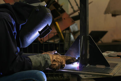 Side view of worker welding metal in workshop