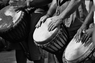 Midsection of men playing drums