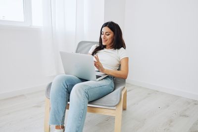 Young woman using laptop while sitting on sofa at home