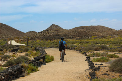 Rear view of man walking on mountain against sky