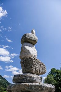 Low angle view of stone stack on rock against sky