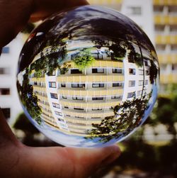 Close-up of hand holding glass with reflection of man