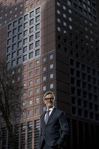 Grey-haired businessman in front of red skyscraper