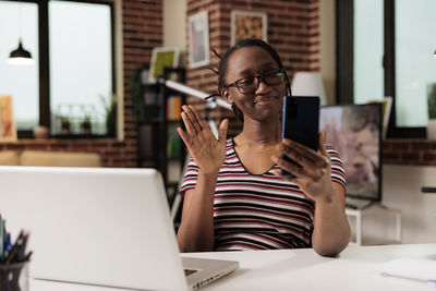 Young woman using laptop while sitting on table