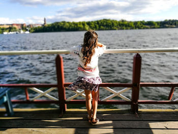 Rear view of woman standing on footbridge over river