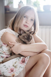 Portrait of blondie girl with burmese cat at home