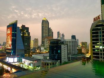 Illuminated buildings in city against sky during sunset