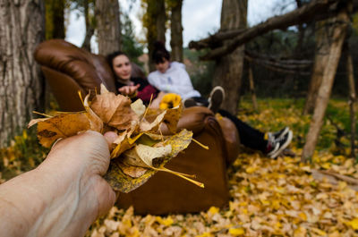 Midsection of man holding autumn leaves on land