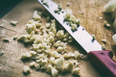 High angle view of chopped garlic and kitchen knife on cutting board