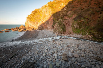 Scenic view of rocks on beach against sky