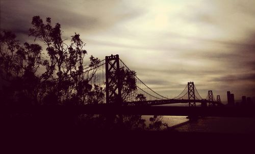 Bridge over river against cloudy sky