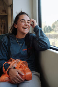 Full length of teenage girl sitting on window