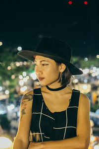 Close-up of woman wearing hat at night