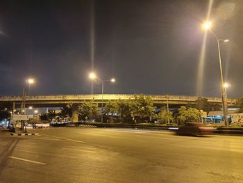 Illuminated city street against sky at night