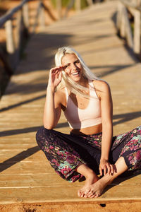 Cheerful young woman sitting on boardwalk