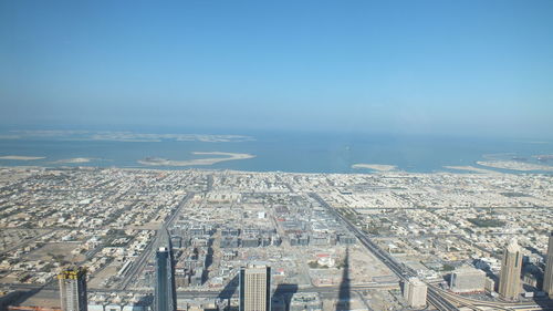 Cityscape at coastline against clear blue sky seen through burj khalifa