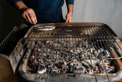 High angle view of man preparing fish on barbecue grill