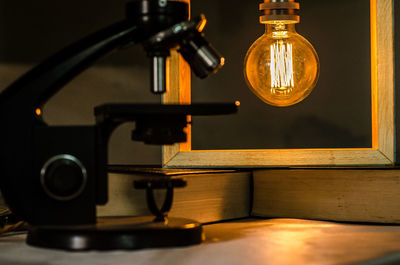 Microscope against illuminated light bulb picture frame in darkroom