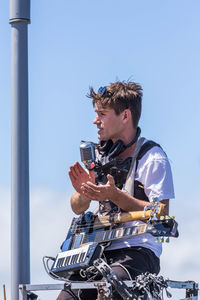 Young man using smart phone against sky