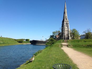 Church by river against blue sky