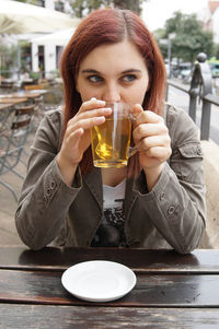 Young woman having drink while sitting at outdoor cafe