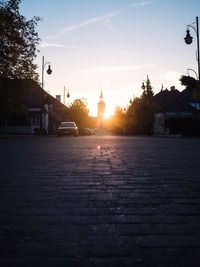 Surface level of street by buildings against sky during sunset