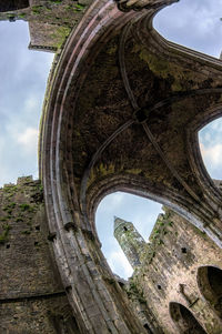 Low angle view of old ruin building against cloudy sky