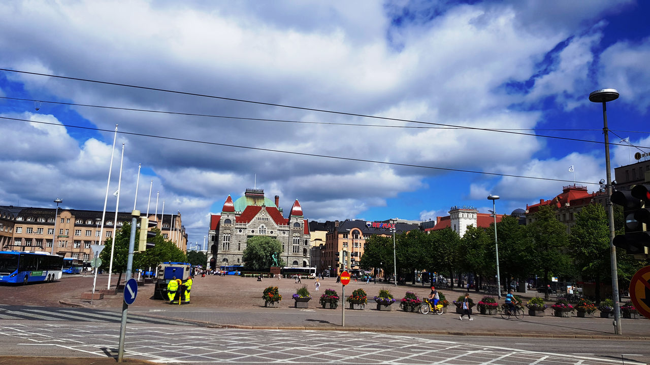 GROUP OF PEOPLE WALKING ON ROAD AGAINST BUILDINGS