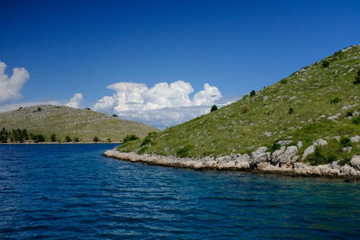 Scenic view of sea and mountains against blue sky