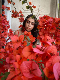 Young woman standing by pink flowering plants