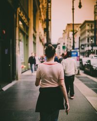 Rear view of people walking on city street