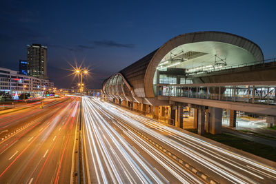 Light trails on bridge in city against sky at night