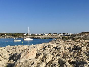 Sailboats in sea against clear blue sky