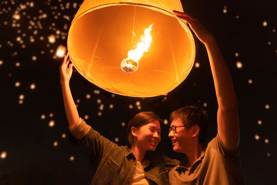 Couple holding lit paper lantern at night