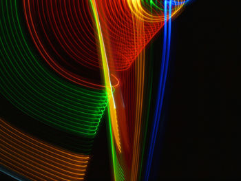 Close-up of multi colored light trails against black background