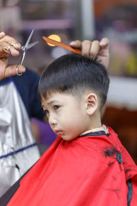 Hairdresser cutting boy hair in salon