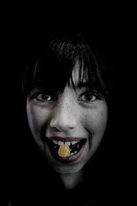 Close-up portrait of smiling man against black background