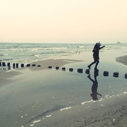 Side view of woman on stepping stones in sea