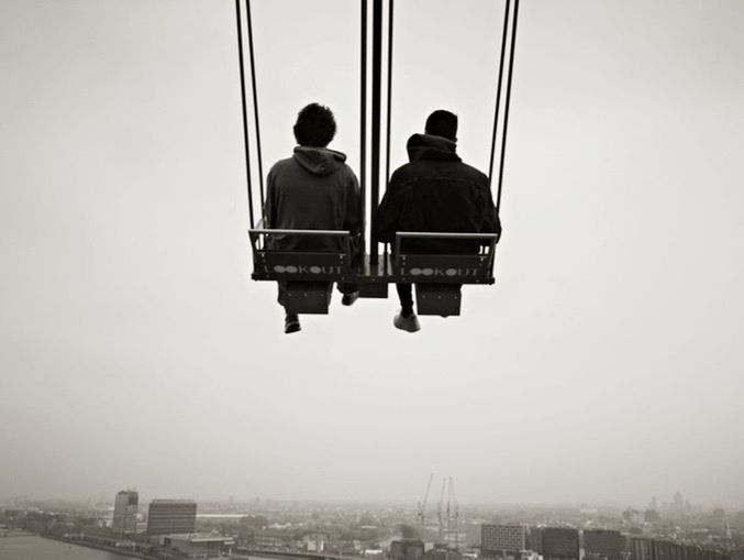 REAR VIEW OF MAN AND WOMAN LOOKING AT VIEW OF BUILDINGS